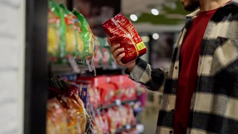 Close-up,-a-brunette-man-took-a-product-from-a-supermarket-counter-and-twirls-it-in-his-hands-during-inspection-after-which-he-returns-it-to-its-place