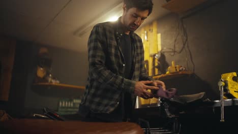 Confident-guy-in-a-checkered-shirt-puts-tools-in-his-box-after-repairing-a-motorcycle-in-a-workshop