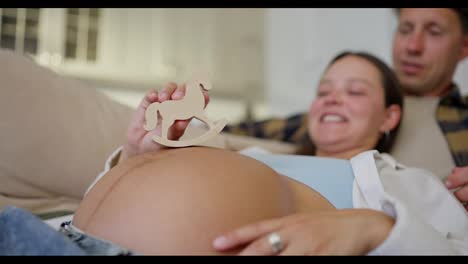 Close-up-of-a-happy-woman-with-her-husband-expecting-a-baby-and-playing-with-small-toys-during-pregnancy