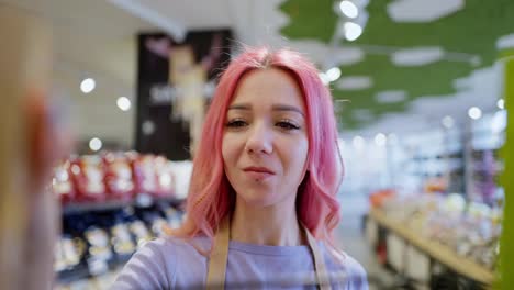 close-up-of-a-happy-girl-with-pink-hair-a-supermarket-worker-lays-out-goods-on-the-counter.-A-girl-supermarket-worker-lays-out-goods-on-the-shelves