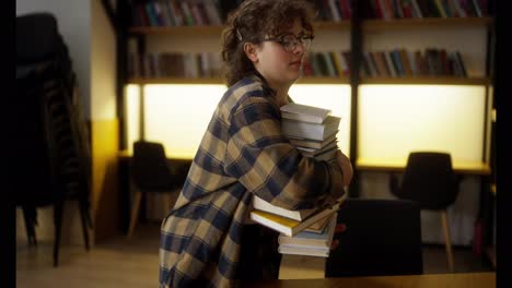 A-girl-with-curly-hair-a-student-carries-a-heavy-stack-of-books-that-crumbles-in-her-hands-in-the-library