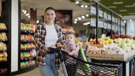 Retrato-De-Una-Niña-Morena-Feliz-Con-Una-Camisa-A-Cuadros-Junto-Con-Su-Pequeña-Hija-Mientras-Compran-En-Un-Supermercado.