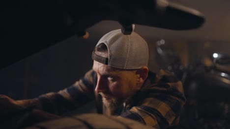 Close-up-of-a-mechanic-guy-in-a-checkered-shirt-repairing-a-motorcycle-in-a-studio-workshop-during-a-working-day