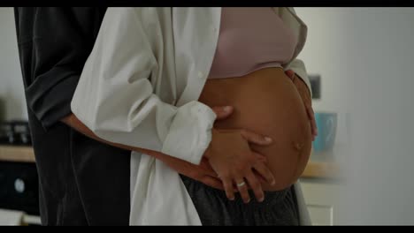 Close-up-of-a-happy-pregnant-woman-slow-dancing-with-her-husband-in-the-kitchen-in-the-morning