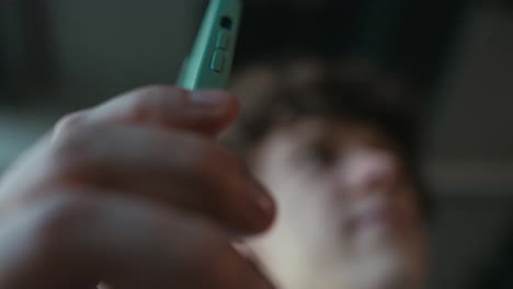 Close-up-a-guy-with-curly-hair-takes-out-a-green-smartphone-from-his-pants-pocket-and-begins-business-communication-in-the-office