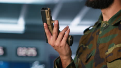 Close-up-of-soldier-holding-pistol,-managing-combat-load-equipment