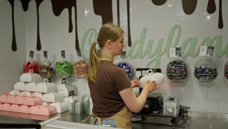 Portrait-of-a-confident-and-happy-girl-worker-in-the-confectionery-department-smiling-and-posing-in-a-brown-T-shirt-and-apron-in-a-supermarket