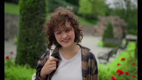 Portrait-of-a-happy-brunette-girl-in-a-plaid-shirt-with-a-backpack-walking-in-the-park-while-studying-at-the-university