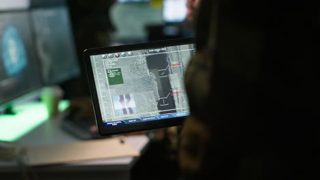 Close-up-shot-of-officer-using-software-on-device-to-do-assessment-of-enemy