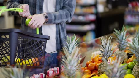 Close-up-a-supermarket-customer-in-a-plaid-shirt-selects-the-fruit-he-needs-among-the-orange-mango-and-pineapple-fruits-in-the-supermarket