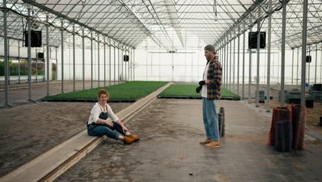 A-loving-couple-of-farmers,-a-girl-with-red-hair-and-her-boyfriend-in-a-cap-have-fun-while-designing-a-new-greenhouse-and-making-their-plans-in-working-on-the-farm