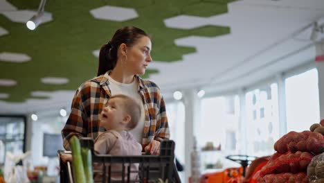 Confident-brunette-girl-in-a-plaid-shirt,-mother-of-a-little-girl-shopping-with-her-daughter-in-the-supermarket