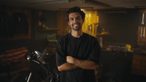 Retrato-De-Un-Chico-Moreno-Feliz-Con-Barba-Incipiente-Y-Camiseta-Gris-Que-Posa-Desde-Su-Taller.