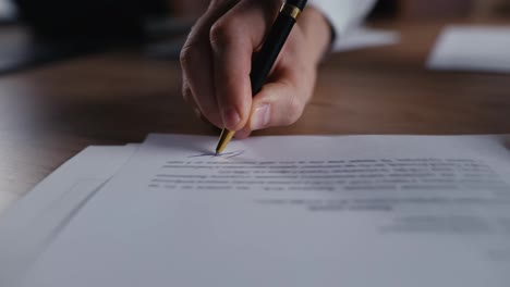 Close-up-a-guy-in-a-white-shirt-writes-his-signature-with-blue-ink-on-a-white-sheet-of-document-using-a-black-pen-in-the-office