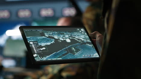 Military-agent-working-in-control-room,-using-software-on-tablet