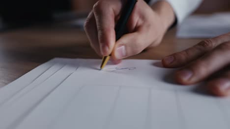 Close-up-of-a-guy-in-a-white-shirt-makes-a-painting-on-a-sheet-of-paper-using-a-black-pen-while-working-in-the-office