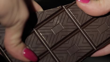 Woman-breaks-black-chocolate-bar.-Close-up.-Slow-motion