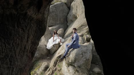 Groom-with-bride-sit-on-a-high-slope-of-the-mountain.-Wedding-couple.-Happy