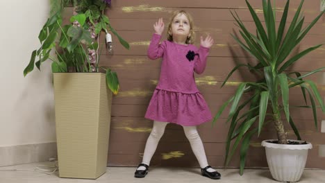 Little-child-dance-near-flowerpots-and-wooden-fence.-Feel-happy,-smiling