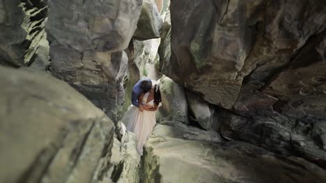 Groom-with-bride-standing-in-cave-of-mountain-hills.-Wedding-couple-in-love