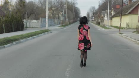 Una-Joven-Atractiva-Con-Un-Vestido-Con-Flores-Corriendo-Por-La-Carretera.