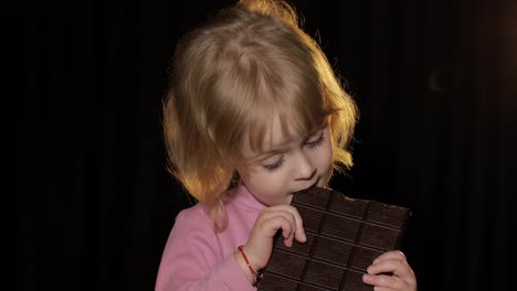 Attractive-child-eating-a-huge-block-of-chocolate.-Cute-blonde-girl