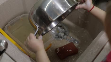 Child-washing-dishes-in-the-kitchen.-Close-up-of-girls-hands