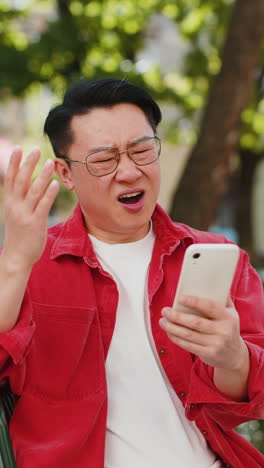 Surprised-Asian-man-use-smartphone-loses,-bad-news,-fortune-loss,-fail-outdoors-in-city-street