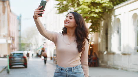 Una-Bloguera-India-Se-Toma-Una-Selfie-Con-Un-Teléfono-Inteligente-Y-Realiza-Una-Videollamada-En-Línea-Con-Sus-Suscriptores-En-Una-Calle-De-La-Ciudad