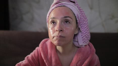 Mujer-Viendo-Una-Película-Nocturna-En-La-Televisión,-Comiendo-Palomitas-De-Maíz.-Bata-De-Baño,-Mascarilla-Facial