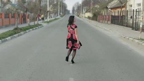 Una-Joven-Atractiva-Con-Un-Vestido-Con-Flores-Caminando-Por-La-Carretera.