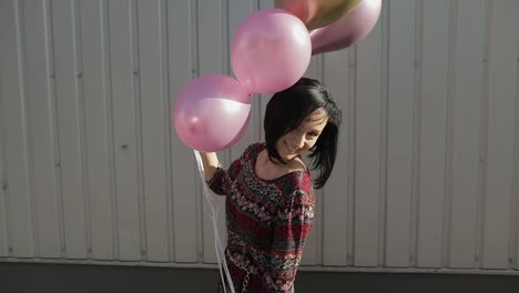 Pretty-woman-in-dress-holding-balloons-with-helium-outdoors-in-daylight