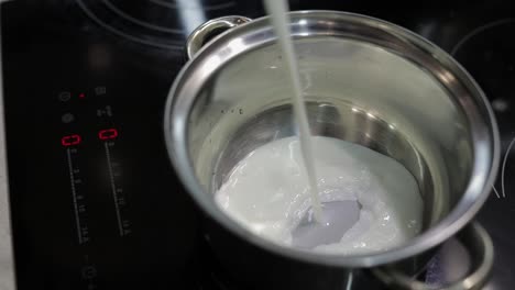 Milk-being-poured-into-the-stainless-steel-pot-for-cooking-in-kitchen