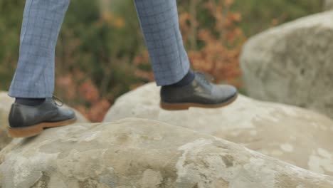 Man-feets-stepping-over-boulders-mountains-near-forest.-Hill-of-a-high-mountain