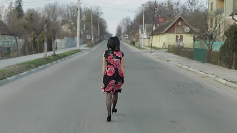 Una-Joven-Atractiva-Con-Un-Vestido-Con-Flores-Caminando-Por-La-Carretera.