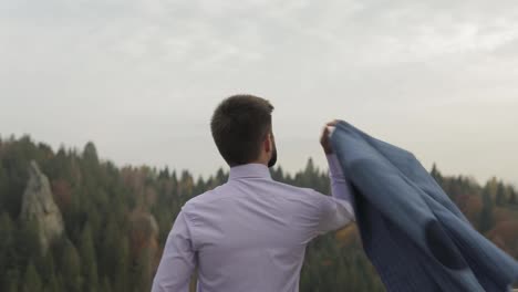 Young-man-on-the-hill-of-a-mountain-with-jacket.-Businessman.-Bridegroom.-Groom