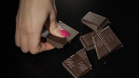 Woman-breaks-black-chocolate-bar.-Close-up.-Slow-motion