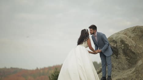 Newlyweds-stand-on-a-high-slope-of-the-mountain.-Groom-and-bride