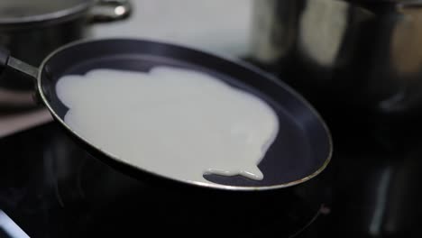 The-process-of-cooking-homemade-pancakes.-Woman-pours-pancake-dough-on-pan