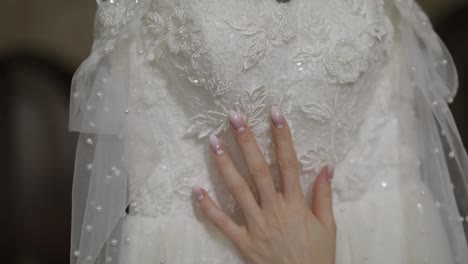 Hand-of-beautiful-bride-touches-wedding-dress.-Pretty-and-well-groomed-woman