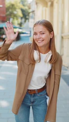 Caucasian-woman-smiling-friendly-at-camera,-hello-waving-hands-gesturing-hi,-greeting-on-city-street