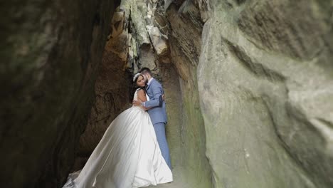 Groom-with-bride-standing-in-cave-of-mountain-hills.-Wedding-couple-in-love