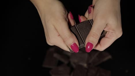 Woman-breaks-black-chocolate-bar.-Close-up.-Slow-motion