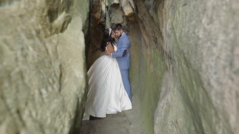 Groom-with-bride-standing-in-cave-of-mountain-hills.-Wedding-couple-in-love