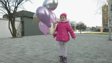 Glückliches-Kind-Springt-Mit-Heliumballons-Auf-Der-Straße