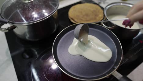 The-process-of-cooking-homemade-pancakes.-Woman-pours-pancake-dough-on-pan