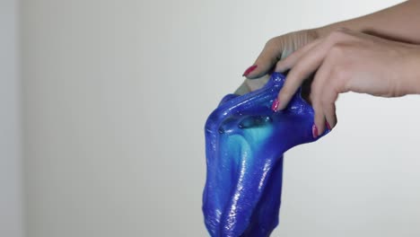 Woman-hands-playing-with-oddly-satisfying-blue-slime-gooey-substance.-Antistress