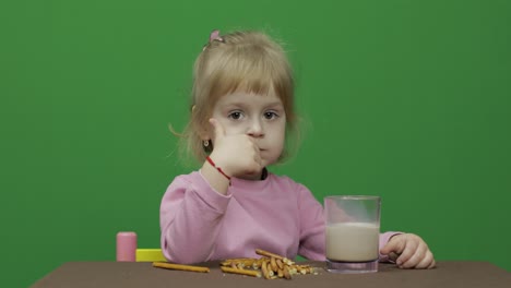 The-child-eats-cookies.-A-little-girl-is-eating-cookies-sitting-on-the-table.