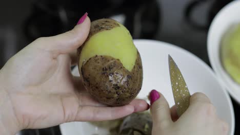 Female-housewife-hands-peeling-potatoes-in-the-kitchen.