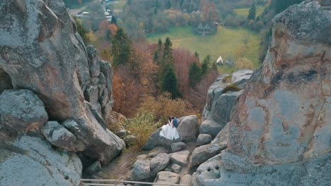 Newlyweds-stand-on-a-high-slope-of-the-mountain.-Groom-and-bride.-Arial-view